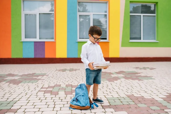 Cute schoolboy in white shirts and a glasses with books and a backpack. Back to school