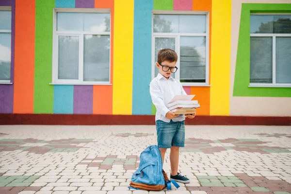 学校の外で悲しい少年 現代の学校の近くに本を持つ悲しい小学生 学校のコンセプト 学校に戻る — ストック写真