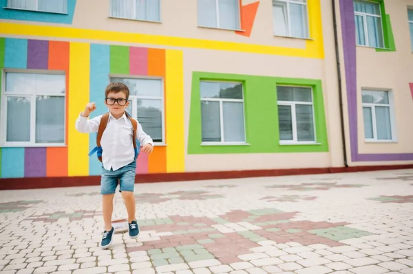 学校に戻る ガラスの中で幸せな笑顔の男の子は初めて学校に行く予定です バックパック付きの子供と屋外で予約する レッスン開始 秋の初日 — ストック写真