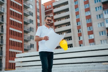 Mimar bir müteahhidin portresi odaların yerleşim planı üzerinde çalışıyor. İnşaat alanındaki belgelerle çalışan ciddi inşaat mühendisi..
