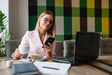 İş kadını kahve / çay içiyor ve kahve dükkanında tablet bilgisayar kullanıyor.