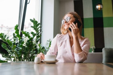 Ofisteki iş kadını arıyor. Ofisten genç bir iş kadını arıyor. Gülümseyen iş kadını. Çatı katında akıllı telefon kullanan genç bir işletme..