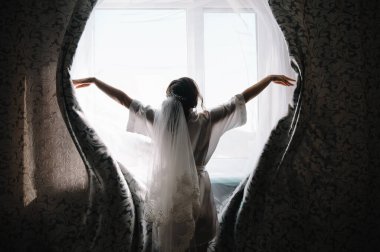 Nedime gelini hazırlıyor. Nedime, gelinin gelinliğini törenden önce bağlamasına yardım eder. Lüks gelinlik yakın plan. En iyi düğün sabahı.