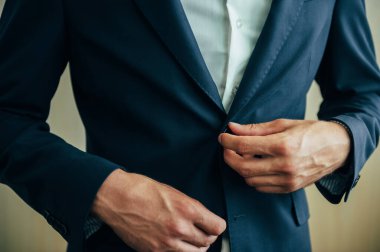 Beyaz gömleğin arka planında erkek elleri kol düğmeleri ve saatlerle kol gömleği, yakın plan çekimleri.