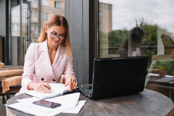 Portrait of young attractive businesswoman examining paperwork in bight light office interior sitting next to the window, business woman read some documents before meeting, filtered image