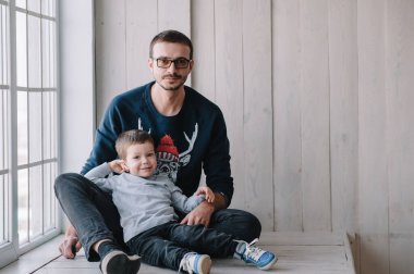 Mutlu adam ve kolları oğlunu kucaklıyor. Aile modu evdeki kanepede. Beyaz gömlek. Babalar Günü.