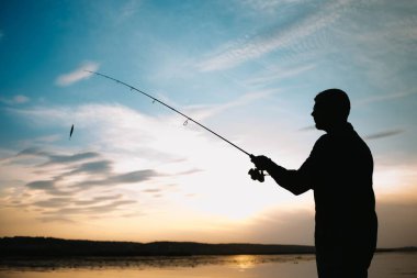 Balık tutma. gün batımında iplik. Bir balıkçı silüeti