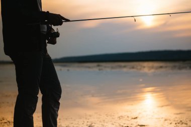 Balıkçının elleri, dönen çubuğu tutar, bobin sapını döndürür. Hobi ve etkinlik
