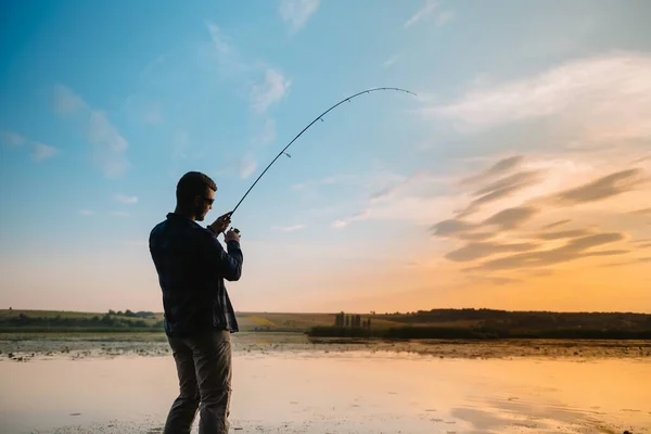 川に沈む夕日の漁師川に沈む夕日と美しい夏の風景 釣りだ 日没時に回転する 漁師のシルエット — ストック写真