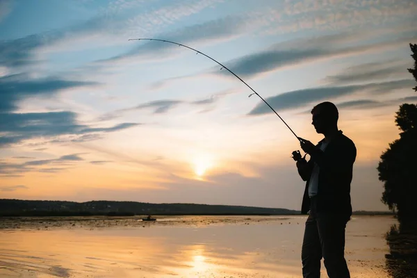 夕暮れ時の漁師のシルエット釣り 淡水漁や魚の捕獲 — ストック写真