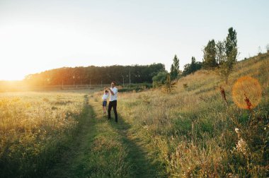 Yakışıklı baba ve küçük tatlı oğlu yeşil çimenlikte eğleniyor ve oynuyorlar. Mutlu aile kavramı. Aile hayatı olan güzel doğa manzarası. Aile birlikte dinleniyor. Babalar Günü