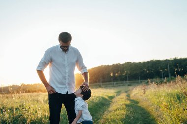 Yakışıklı baba ve küçük tatlı oğlu yeşil çimenlikte eğleniyor ve oynuyorlar. Mutlu aile kavramı. Aile hayatı olan güzel doğa manzarası. Aile birlikte dinleniyor. Babalar Günü