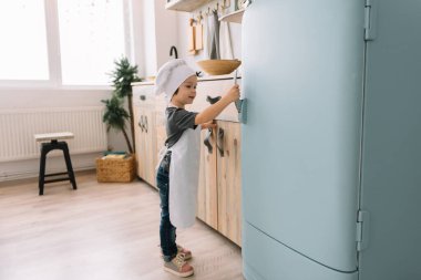 Genç mutlu anne ve bebeği mutfakta kurabiye pişiriyor. Noel ev yapımı zencefilli çörek. Beyaz üniformalı, şapkalı, çikolatalı kurabiyeli tatlı çocuk.
