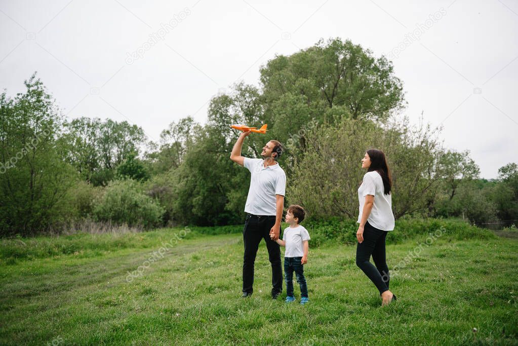 Happy family: mother father and child son on nature on sunset. Mom, Dad and kid laughing and hugging, enjoying nature outside. Sunny day, good mood. concept of a happy family