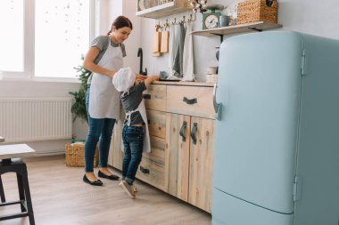 Genç mutlu anne ve bebeği mutfakta kurabiye pişiriyor. Noel ev yapımı zencefilli çörek. Beyaz üniformalı, şapkalı, çikolatalı kurabiyeli tatlı çocuk.