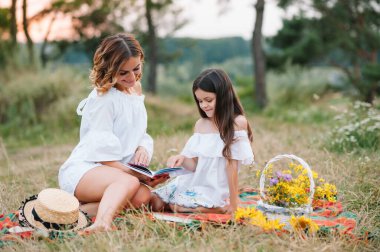 Şık bir anne ve güzel bir kız doğada eğleniyor. Mutlu aile kavramı. Aile hayatı olan güzel doğa manzarası. Aile birlikte dinleniyor. Aile yaşamında mutluluk. Anneler Günü