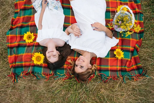 Mutlu bir kadının gülümsemesi ve küçük sevimli çocuğuyla oynaması, açık havada yatması. Sevgi dolu anne ve kızı parkta birlikte vakit geçiriyorlar. Anne ve çocuk eğleniyor. Anneler Günü.