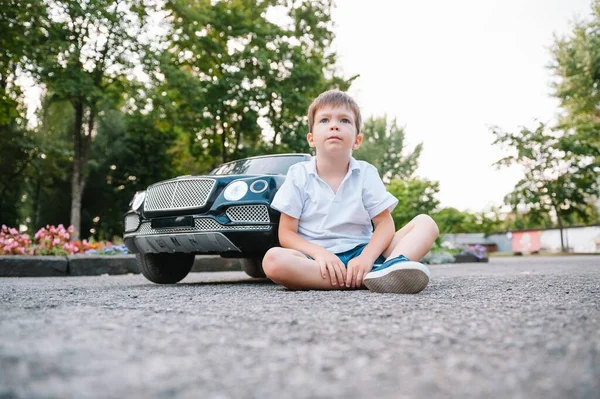 公園で黒い電気自動車に乗ってかわいい少年 面白い少年はおもちゃの電気自動車に乗っています 公園で黒い電気自動車に乗ってる幸せな少年 スペースのコピー — ストック写真