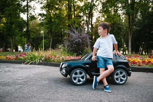 Aranyos Fiú Fekete Elektromos Autóval Parkban Vicces Fiú Egy Játék — Stock Fotó