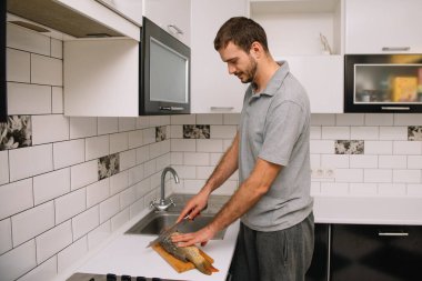 Evdeki mutfakta taze balık kesen adam. Adam aşçı için balık kesiyor.