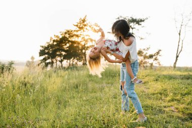 Şık bir anne ve güzel bir kız doğada eğleniyor. Mutlu aile kavramı. Aile hayatı olan güzel doğa manzarası. Aile birlikte dinleniyor. Aile yaşamında mutluluk. Anneler Günü