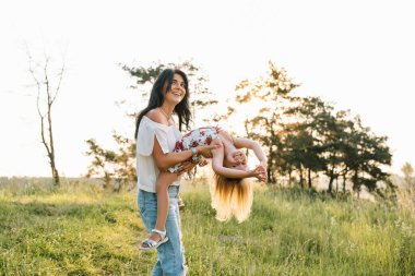 Şık bir anne ve güzel bir kız doğada eğleniyor. Mutlu aile kavramı. Aile hayatı olan güzel doğa manzarası. Aile birlikte dinleniyor. Aile yaşamında mutluluk. Anneler Günü