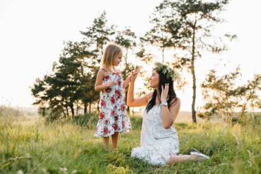 Şık bir anne ve güzel bir kız doğada eğleniyor. Mutlu aile kavramı. Aile hayatı olan güzel doğa manzarası. Aile birlikte dinleniyor. Aile yaşamında mutluluk. Anneler Günü