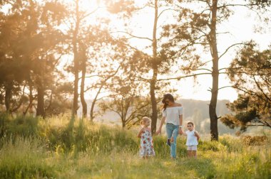 Anne ve iki kızı parkta eğleniyorlar. Aile yaşamında mutluluk ve uyum. Aile hayatı olan güzel doğa manzarası..