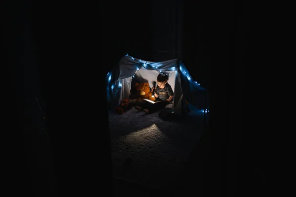 Junge Liest Mit Buch Und Taschenlampe Und Teddybär Zelt Vor — Stockfoto