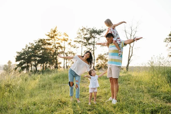 笑顔の若い両親と2人の子供の色の写真 残りの部分と自然の中で楽しみを持っています 幸せな子供時代のライフスタイルのコンセプト — ストック写真
