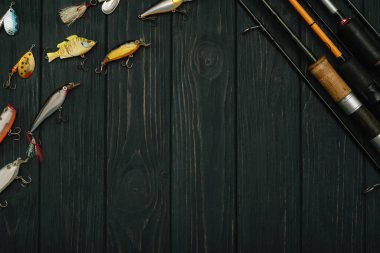 Balıkçılık ekipmanları, balık tutma, kancalar ve karanlık ahşap arka planda yemler. Üst görünüm.