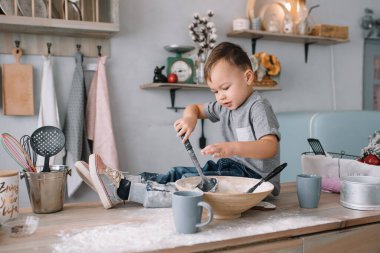 Mutfaktaki yakışıklı çocuk beyaz üniformalı aşçı şefi ve masaların yanında şapka takıyor. Ev yapımı zencefilli ekmek. Çocuk çikolatalı kurabiyeleri pişirdi.