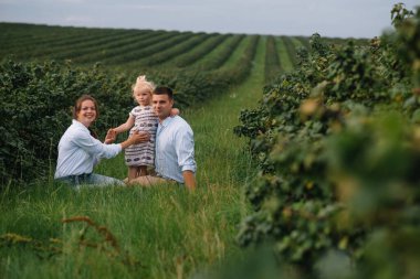 Küçük kızı olan mutlu bir aile güneşli bir arazide birlikte vakit geçiriyor.