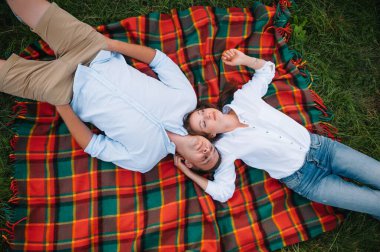 Kızı doğada ebeveynlerine sarılıyor. Anne, baba ve kız çocuğu, çimenlerde yürüyün. Mutlu genç aile birlikte vakit geçiriyor, dışarıda, tatilde, dışarıda. Aile tatili kavramı.