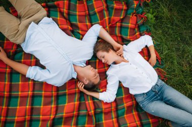 Kızı doğada ebeveynlerine sarılıyor. Anne, baba ve kız çocuğu, çimenlerde yürüyün. Mutlu genç aile birlikte vakit geçiriyor, dışarıda, tatilde, dışarıda. Aile tatili kavramı.