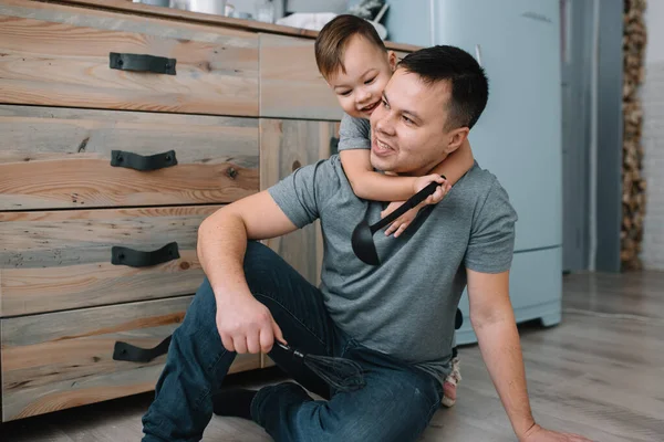 Young man and his son with oven sheet in kitchen. Father with little son on the kitchen