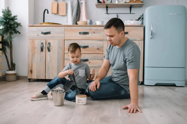 Young man and his son with oven sheet in kitchen. Father with little son on the kitchen