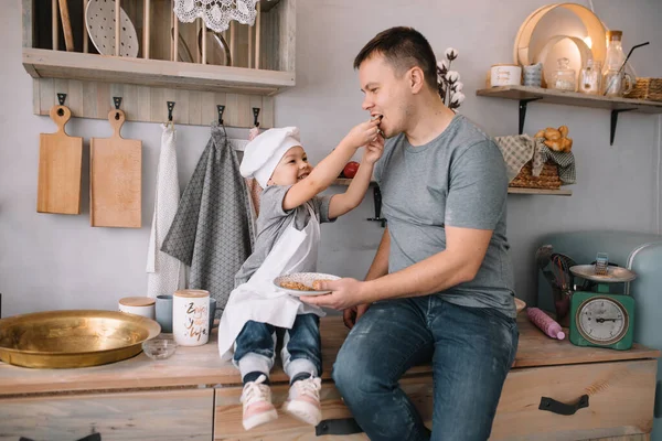 Young man and his son with oven sheet in kitchen. Father with little son on the kitchen