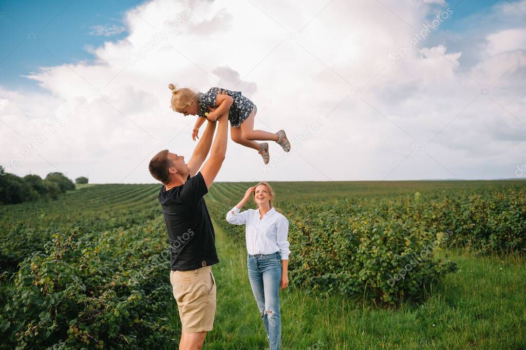 Happy family with little daughter spending time together in sunny field