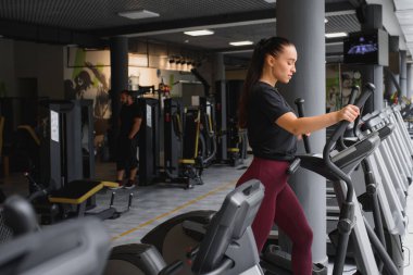 Çekici genç bir kadın koşu bandında koşuyor, fitness spor kulübüne katılıyor.