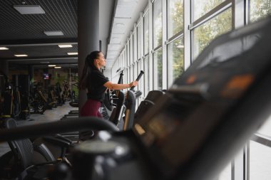 Çekici genç bir kadın koşu bandında koşuyor, fitness spor kulübüne katılıyor.