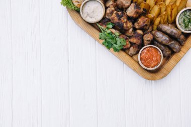 Çoğu et yemeği - sığır kebabı, sosis, mantar, patates, domates ve sos. Bira için en iyi seçim. Beyaz ahşap arka planda yakın plan