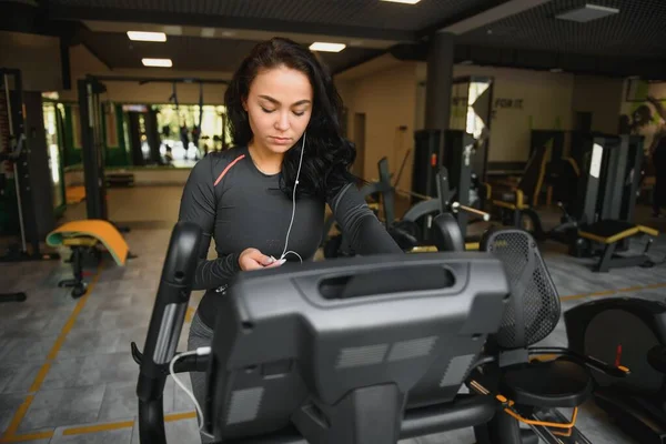 Young Woman Headphones Doing Exercises Stationery Bicycle Gym Fitness Center — Stock Photo, Image