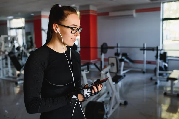 Porträtt Ung Idrottskvinna Med Smartphone Lyssnar Musik Gymmet — Stockfoto