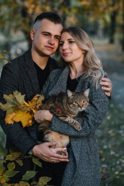 Güz parkında dinlenen genç ve güzel bir çift. Sonbahar konsepti. Sevgili çift kedileriyle dinleniyor..