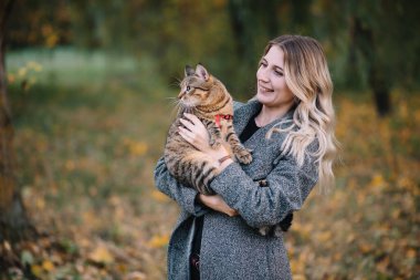 Güz parkında dinlenen genç ve güzel bir çift. Sonbahar konsepti. Sevgili çift kedileriyle dinleniyor..