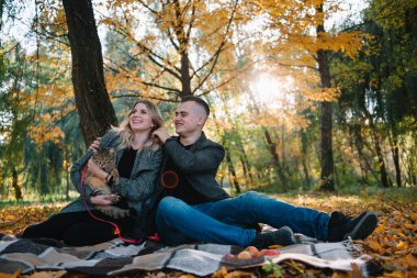 Genç çift sonbahar parkında dinleniyor, erkek kadını kucaklıyor..