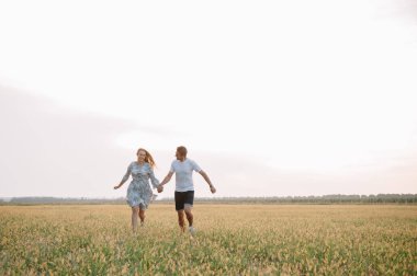 Bir kız ve bir erkek parkta yürüyorlar. Bir çiftin portresi, bir aşk hikayesi. Mutlu gülümseyen, sevgi dolu bir çift, güzel doğayla iç içe. Sevimli.