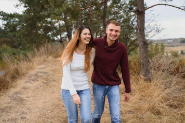 Mutlu ve romantik bir çiftin sonbahar parkında dışarıda vakit geçirmesinin düşük kontrastlı görüntüsü