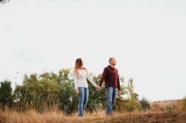 Mutlu ve romantik bir çiftin sonbahar parkında dışarıda vakit geçirmesinin düşük kontrastlı görüntüsü